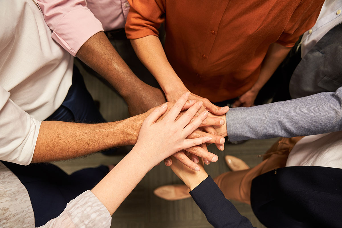 Varias manos apiladas en señal de trabajo en equipo.